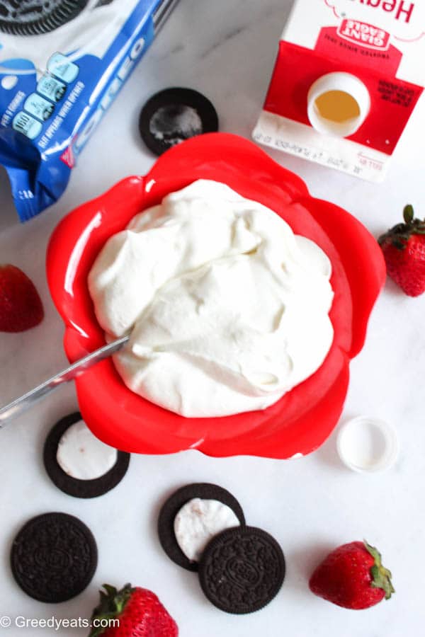 Homemade whipped cream bowl with fresh strawberries and oreo cookies