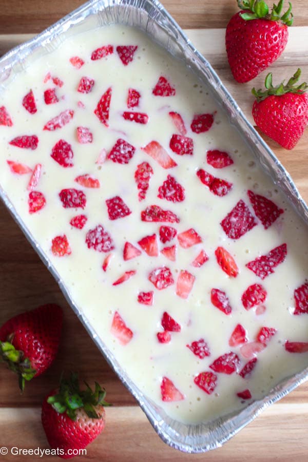 Soft bread batter topped with strawberry chunks ready to be baked.