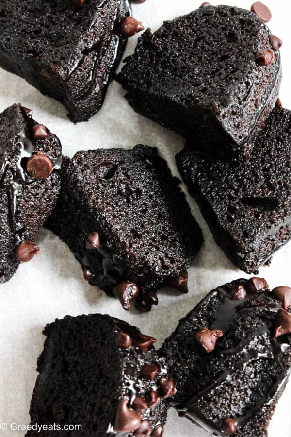 Moist chocolate bundt cake slices drizzled with chocolate ganache and topped with chocolate chips.