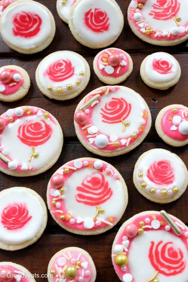 Soft sugar cookies topped with easy royal icing and rose gold sprinkles. Find recipe for these pretty rose cookies on greedyeats.com