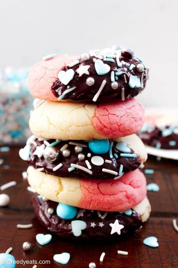 A stack of thick and puffy Neapolitan Holiday Cookies dunked in chocolate and topped with sprinkles.