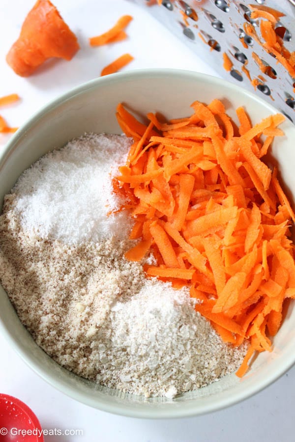 Grated carrots, almond flour, oats flour and coconut flour for carrot cake balls.