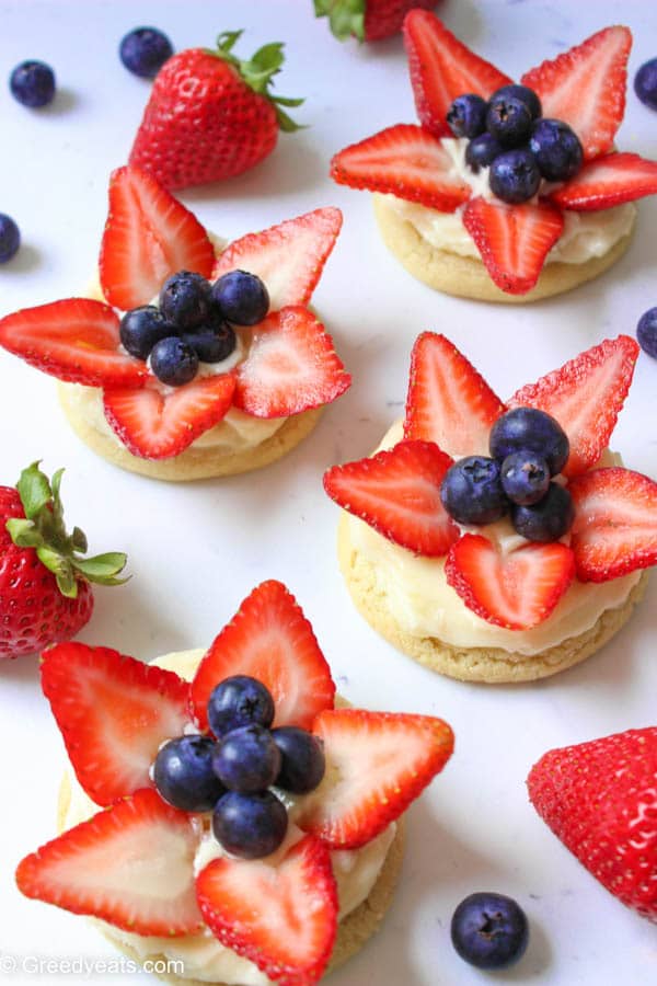 Chewy sugar cookies frosted with creamy lemon frosting and topped with seasonal berries-strawberries and blueberries!