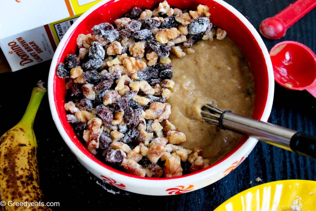 Nuts and raisins to be folded in muffins batter in a bowl.