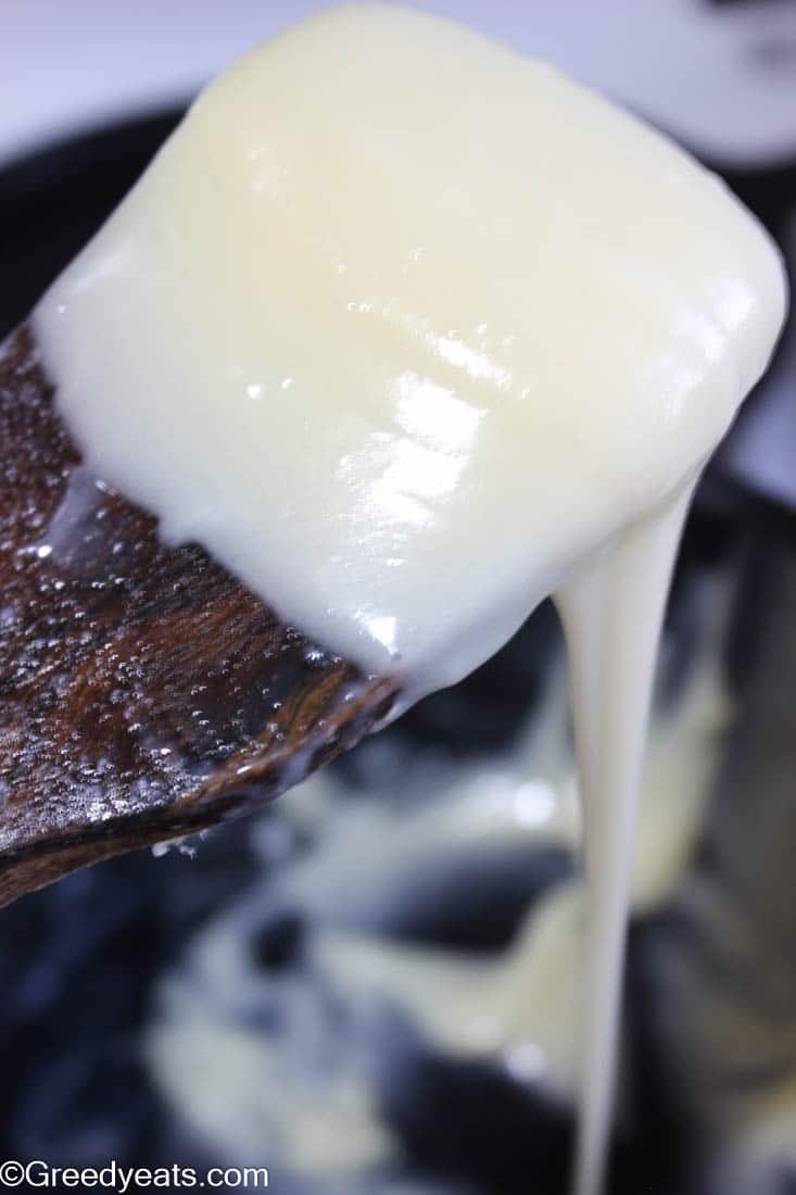 Seriously thick, glossy and creamy condensed milk on a wooden spatula.