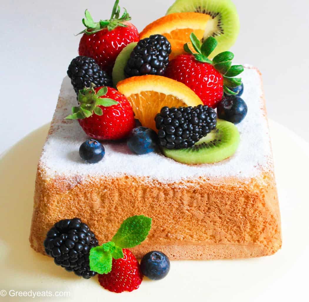 Soft and fluffy Lemon Cake topped with icing sugar, berries, kiwi and oranges