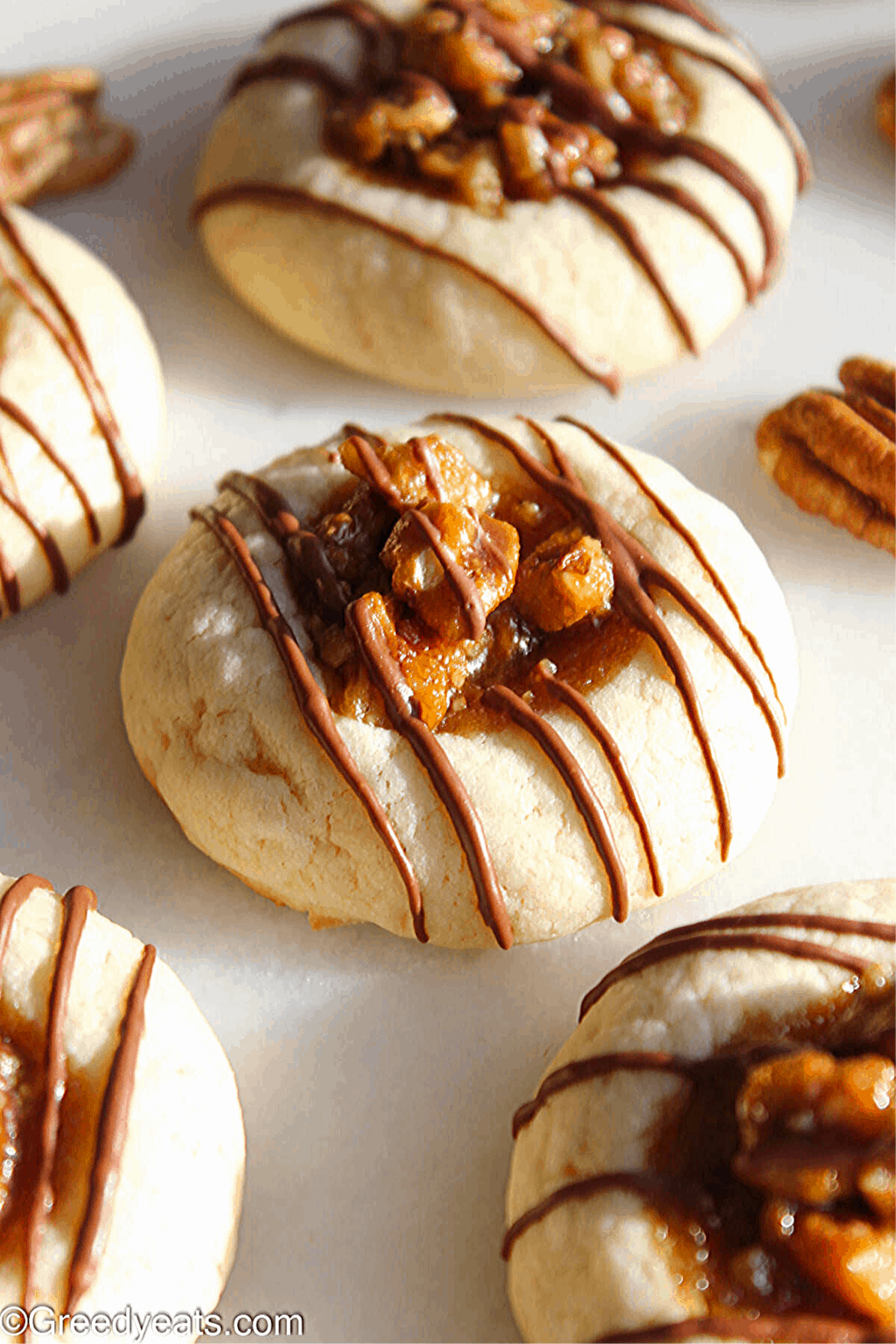 Pecan pie cookies with chocolatw drizzle on a white board.