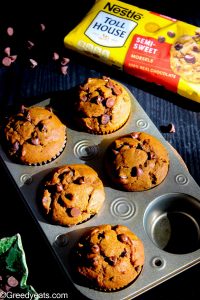 Freshly baked pumpkin muffins with chocolate chips cooling in muffin pan.