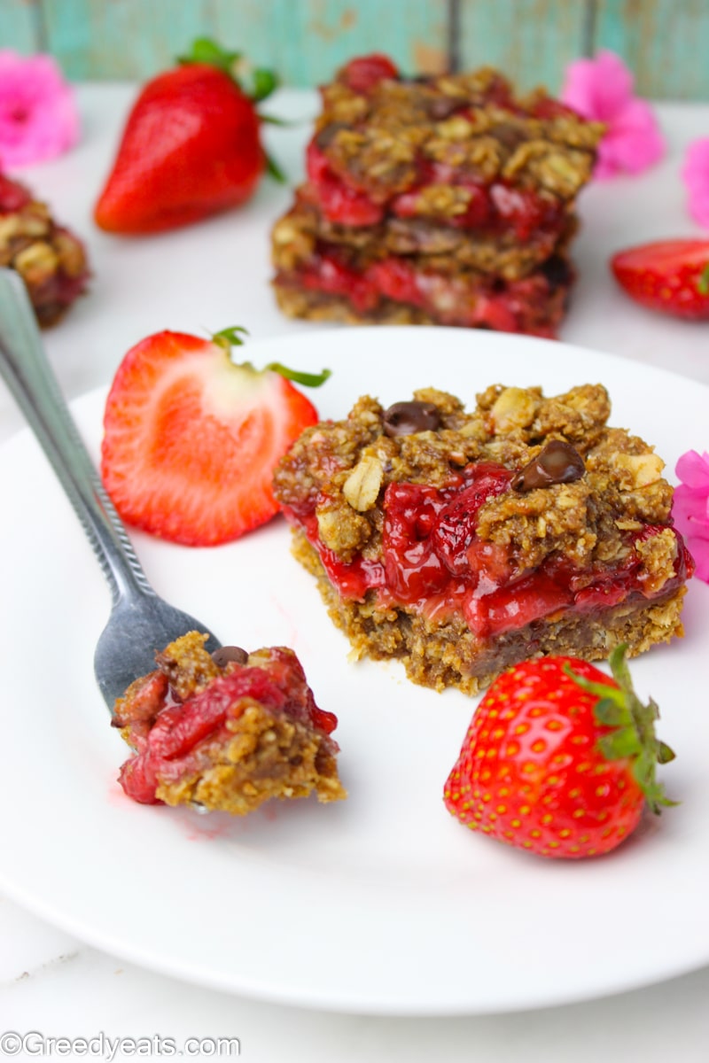 Healthy oats square with juicy strawberry filling on a white plate.