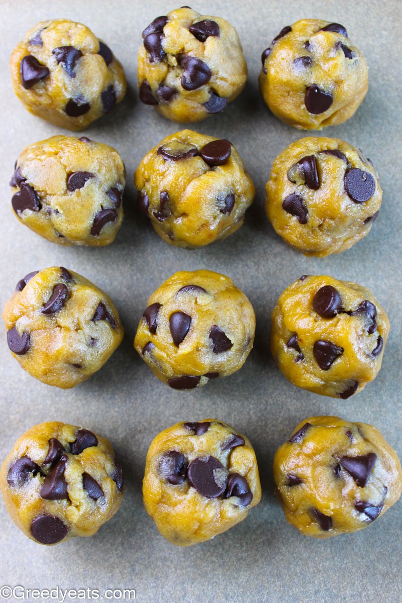 Chilled chocolate chip cookie dough balls on a baking tray lined with parchment paper.