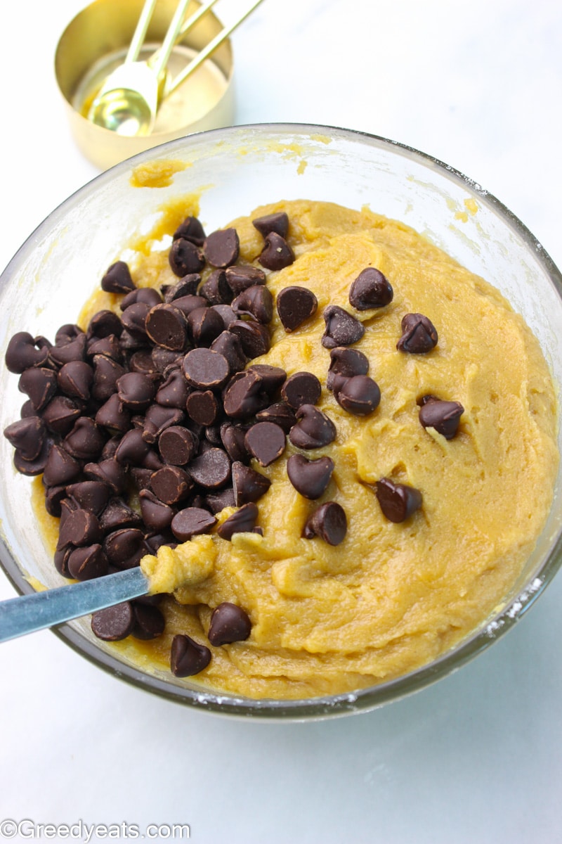 Chocolate chip cookie dough batter in a glass mixing bowl.