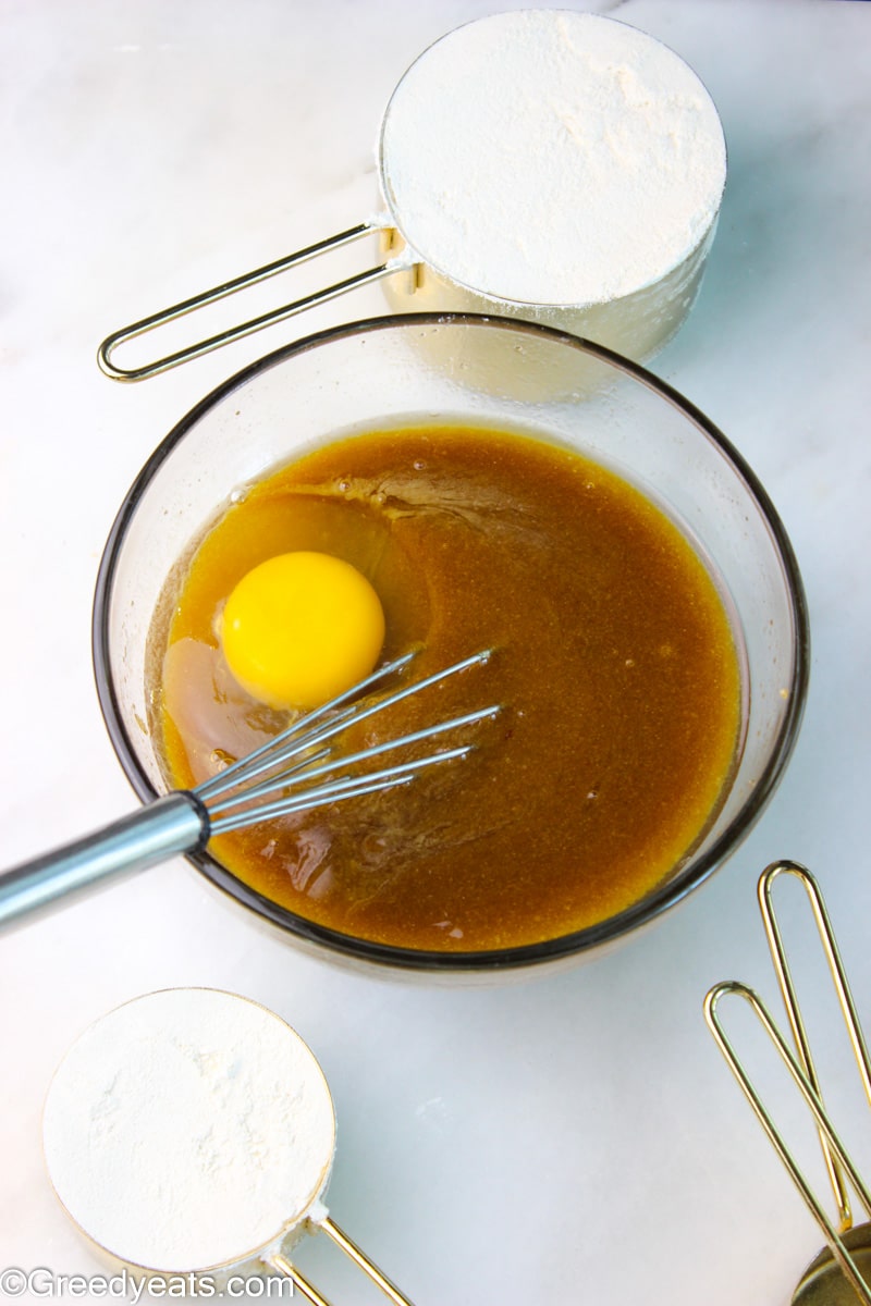 Melted butter, egg and brown sugar whisked in a mixing bowl with a whisk.
