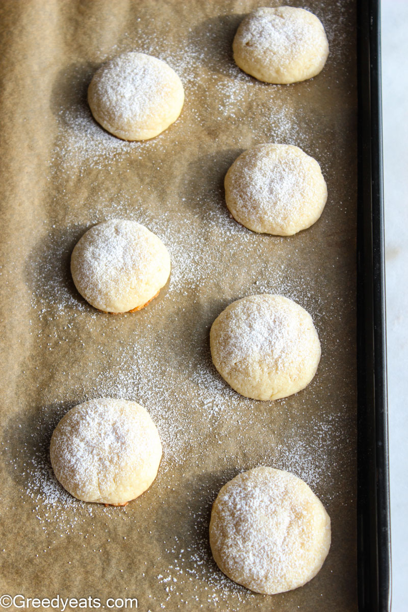 Freshly baked cheese cake cookies cooling down on a baking tray.