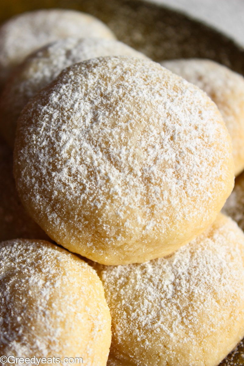 Puffy Cream Cheese Cake Sugar Cookies sprinkled with confectioners' sugar kept on a golden plate. 