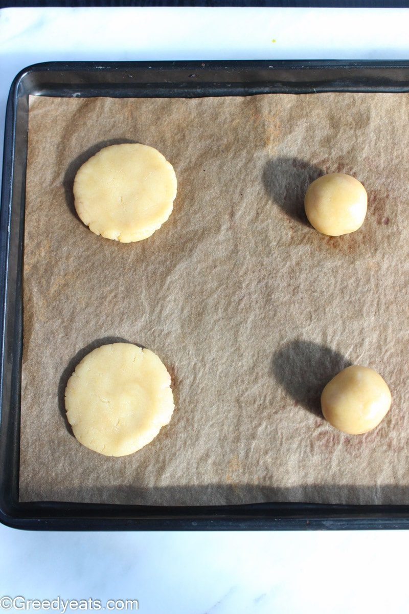 Sugar Cookie balls kept on a baking tray lined with parchment paper.
