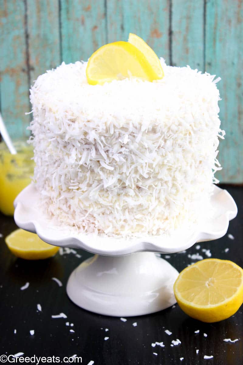 Coconut Cake topped with cream cheese frosting kept on a cake stand.