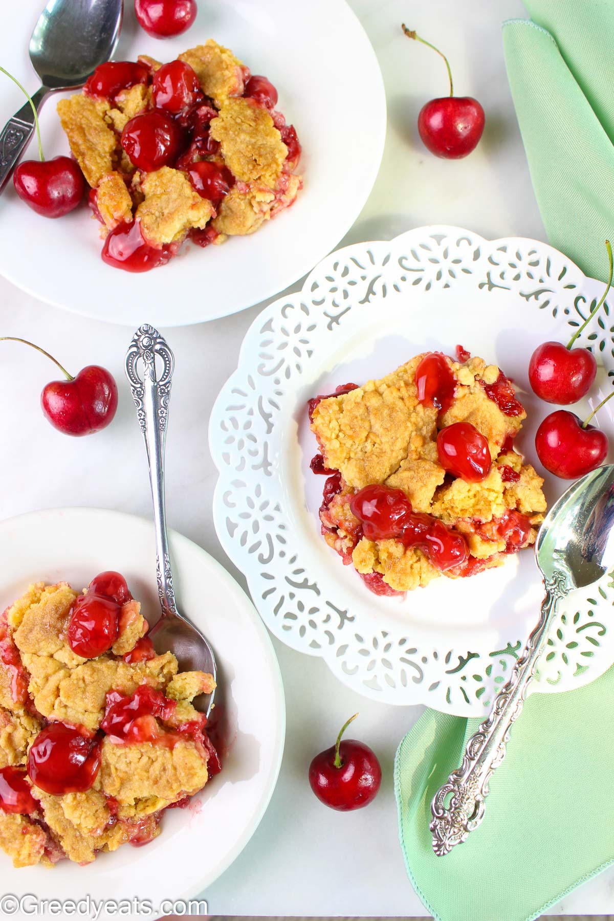 Cherry dump cake slices with fresh cherries served in white plates.