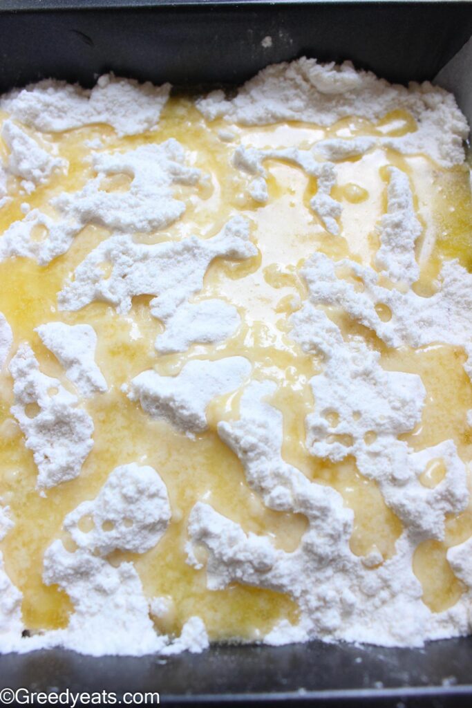 Pouring melted butter over yellow cake mix to make dump cake.