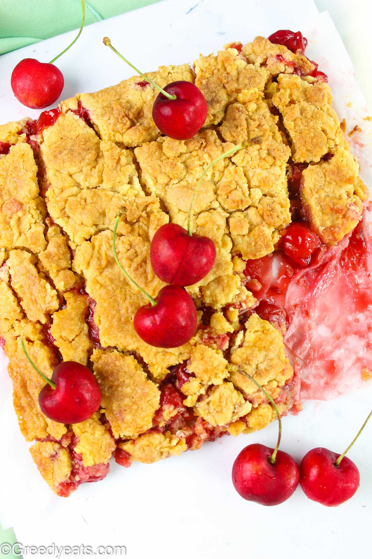 Baked golden brown dump cake topped with a few fresh cherries.