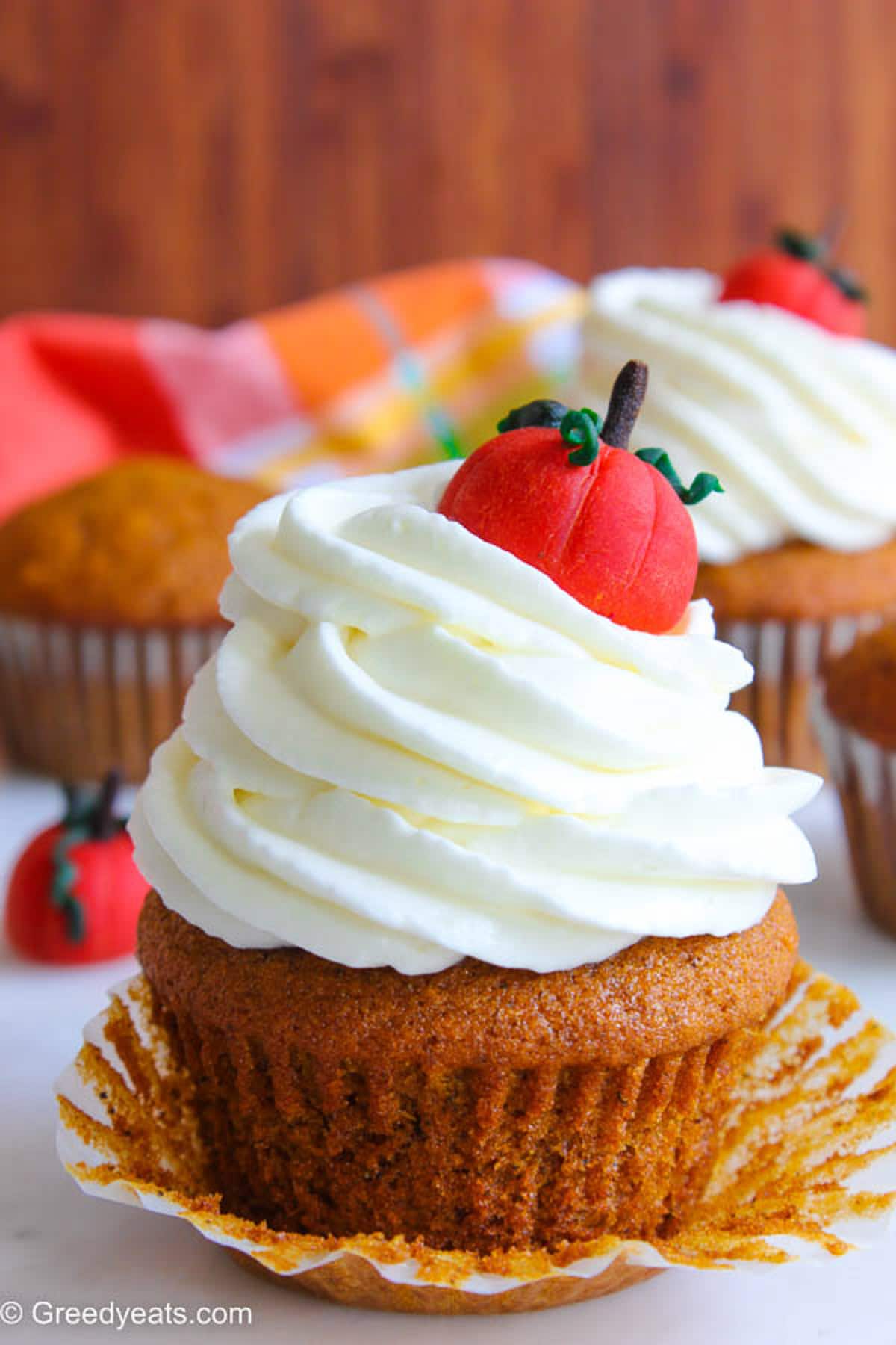 Fluffy and moist Pumpkin Cupcakes with Cream Cheese Frosting swirls and a pumpkin topper.