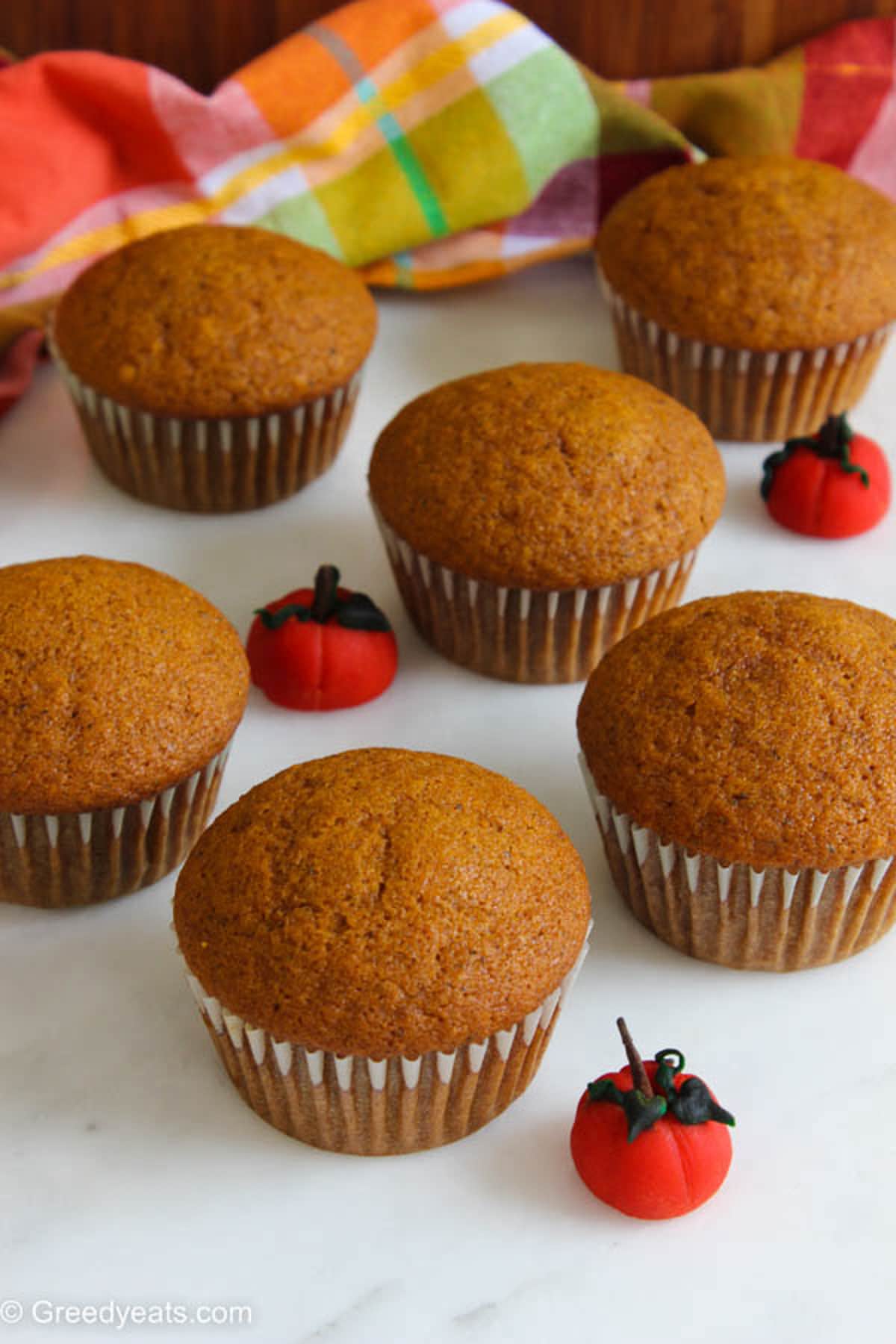 Freshly baked Pumpkin Cupcakes in white cupcake liners, cooling down before frosting.