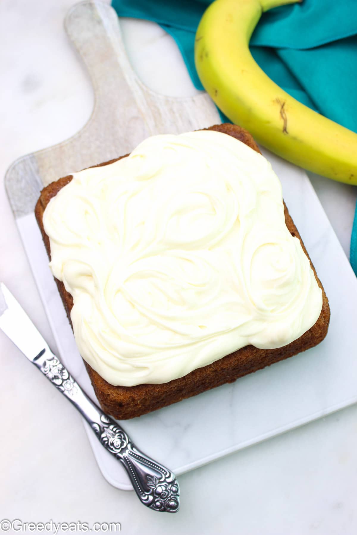 Banana cake topped with a thick layer of cream cheese frosting.
