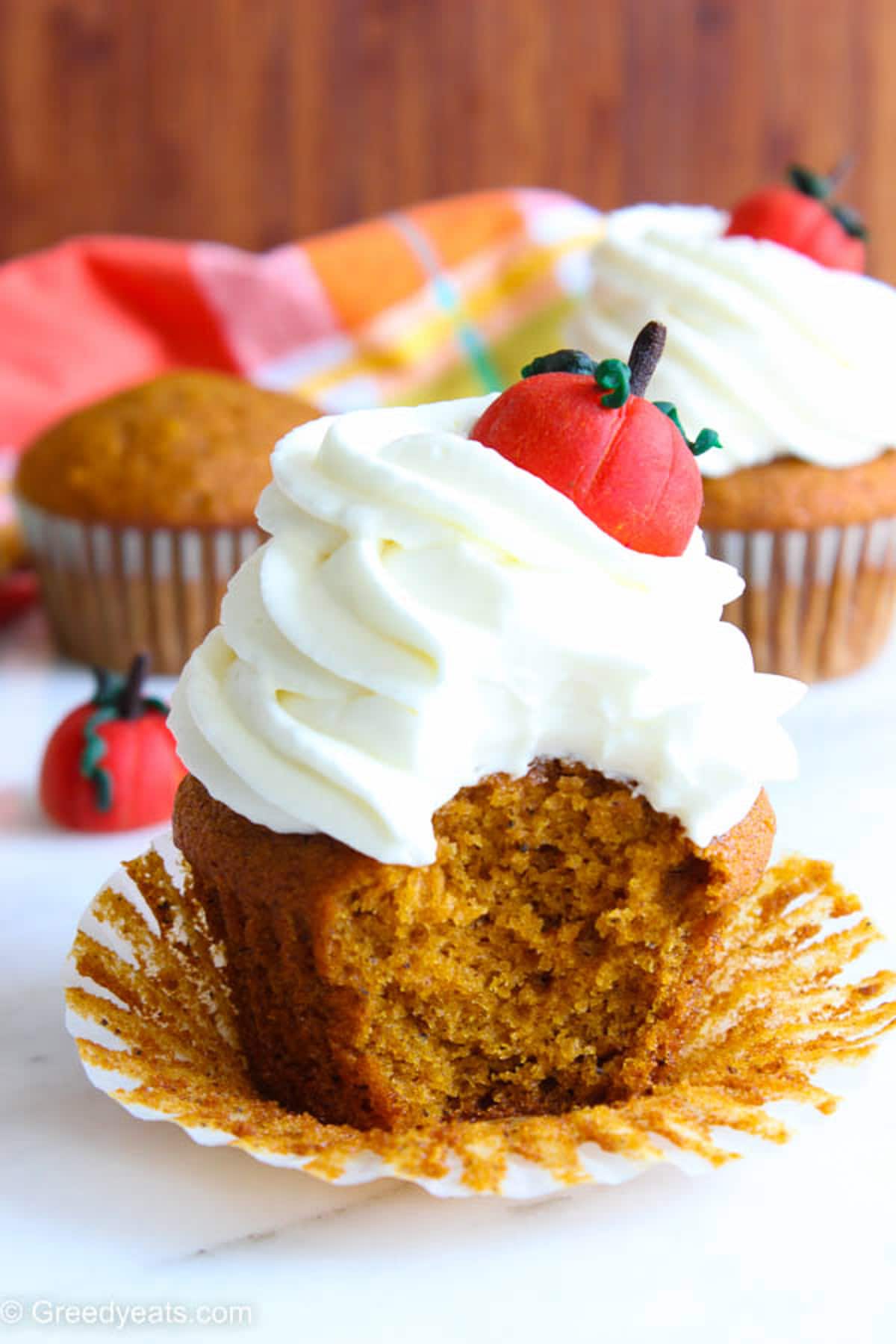 Soft and moist Pumpkin Cupcakes with Cream Cheese Frosting on a white cupcake wrapper.