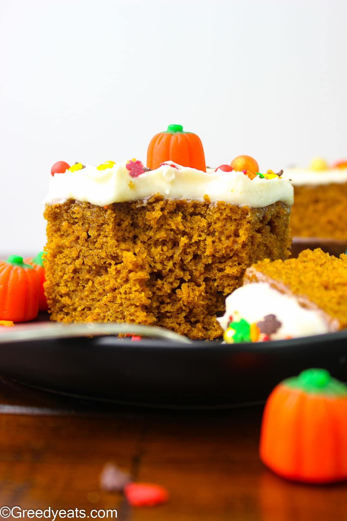 Pumpkin Cake Recipe topped with cream cheese frosting and fall sprinkles.