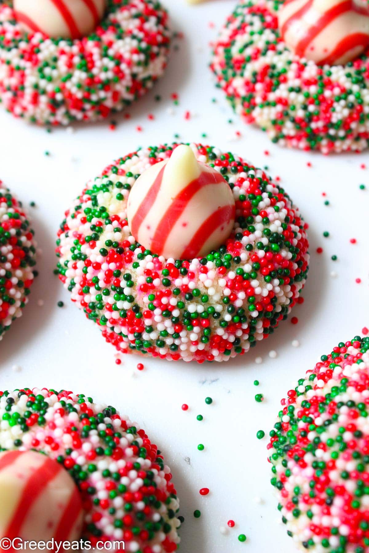 Soft Candy Cane Cookies topped with peppermint kisses and coated in Christmas Sprinkles. 