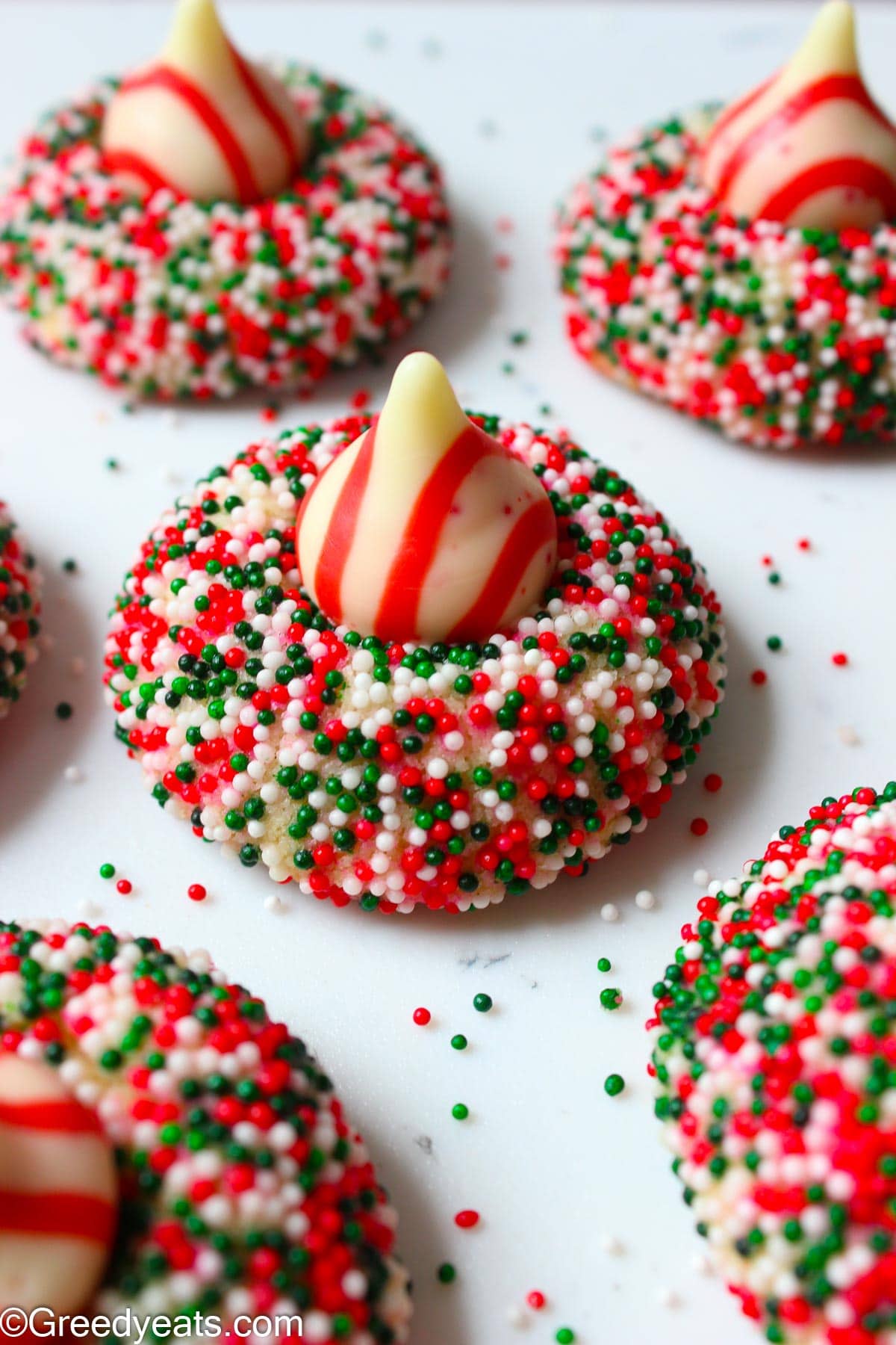 Peppermint Kiss Cookies topped with Holiday Kisses and rolled in Christmas Sprinkles.
