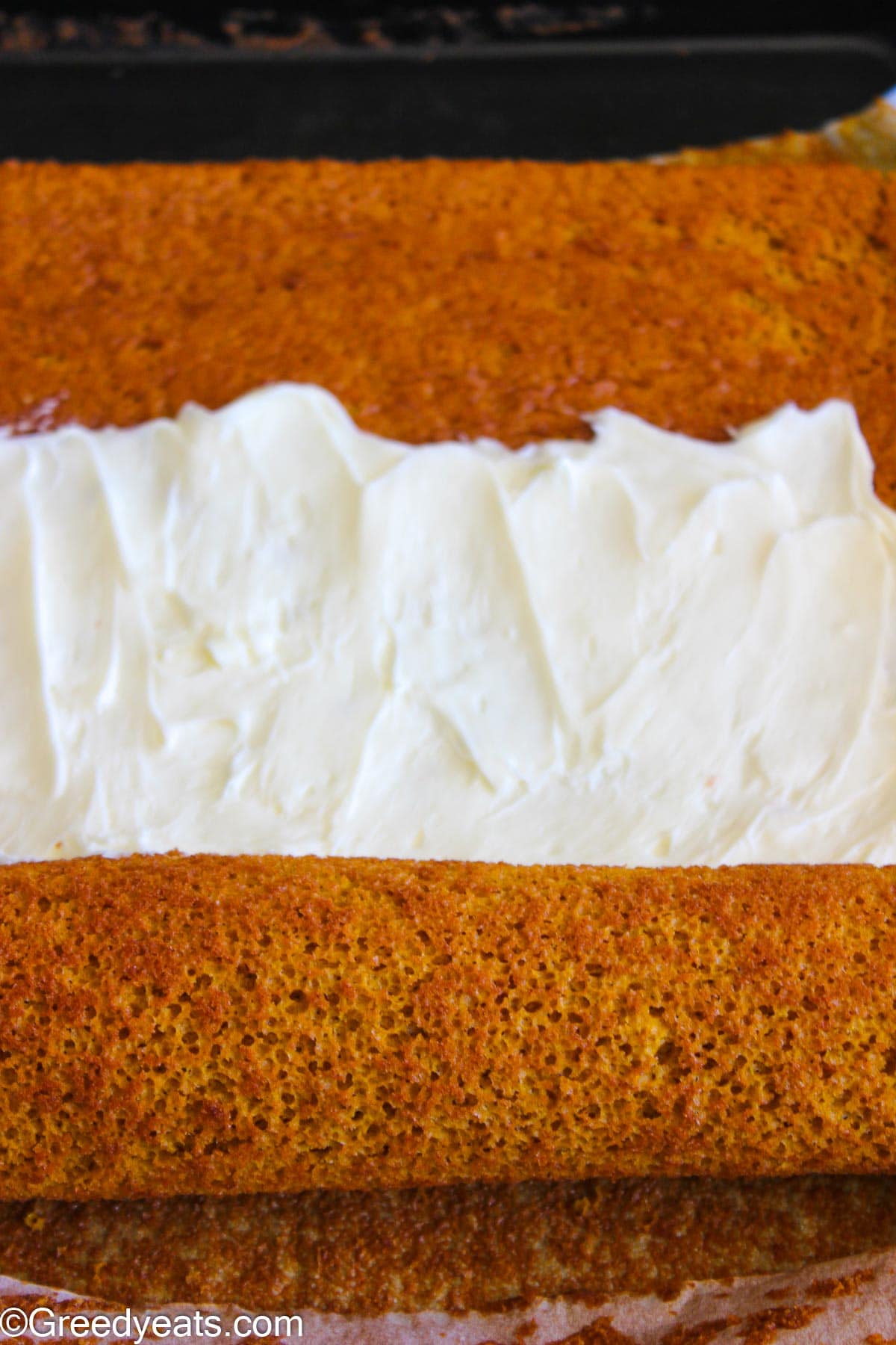 Rolling cooled down pumpkin cake roll with cream cheese frosting in it.