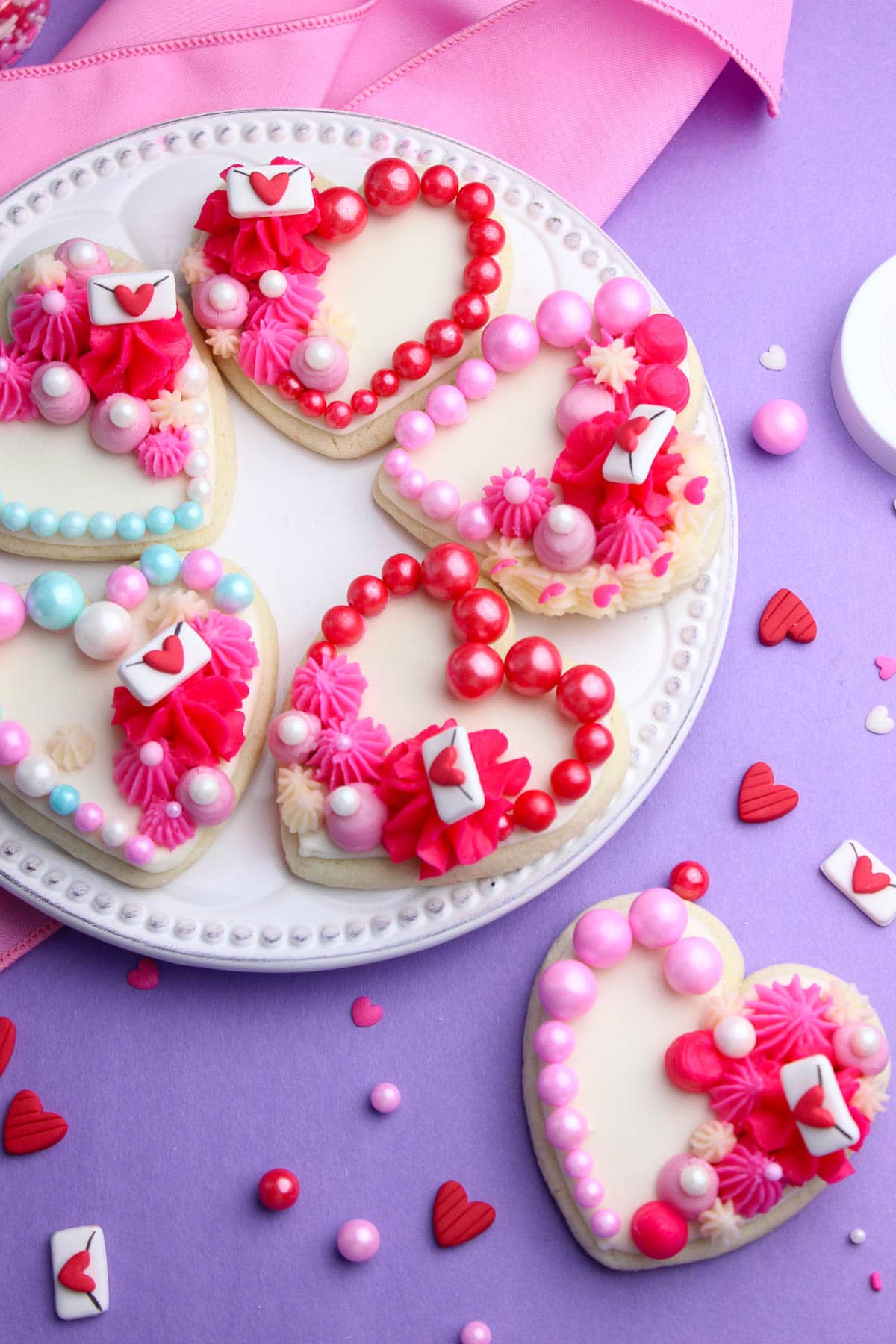 Easy Valentines sugar cookies topped with royal icing, buttercream, love letters and valentines beads.