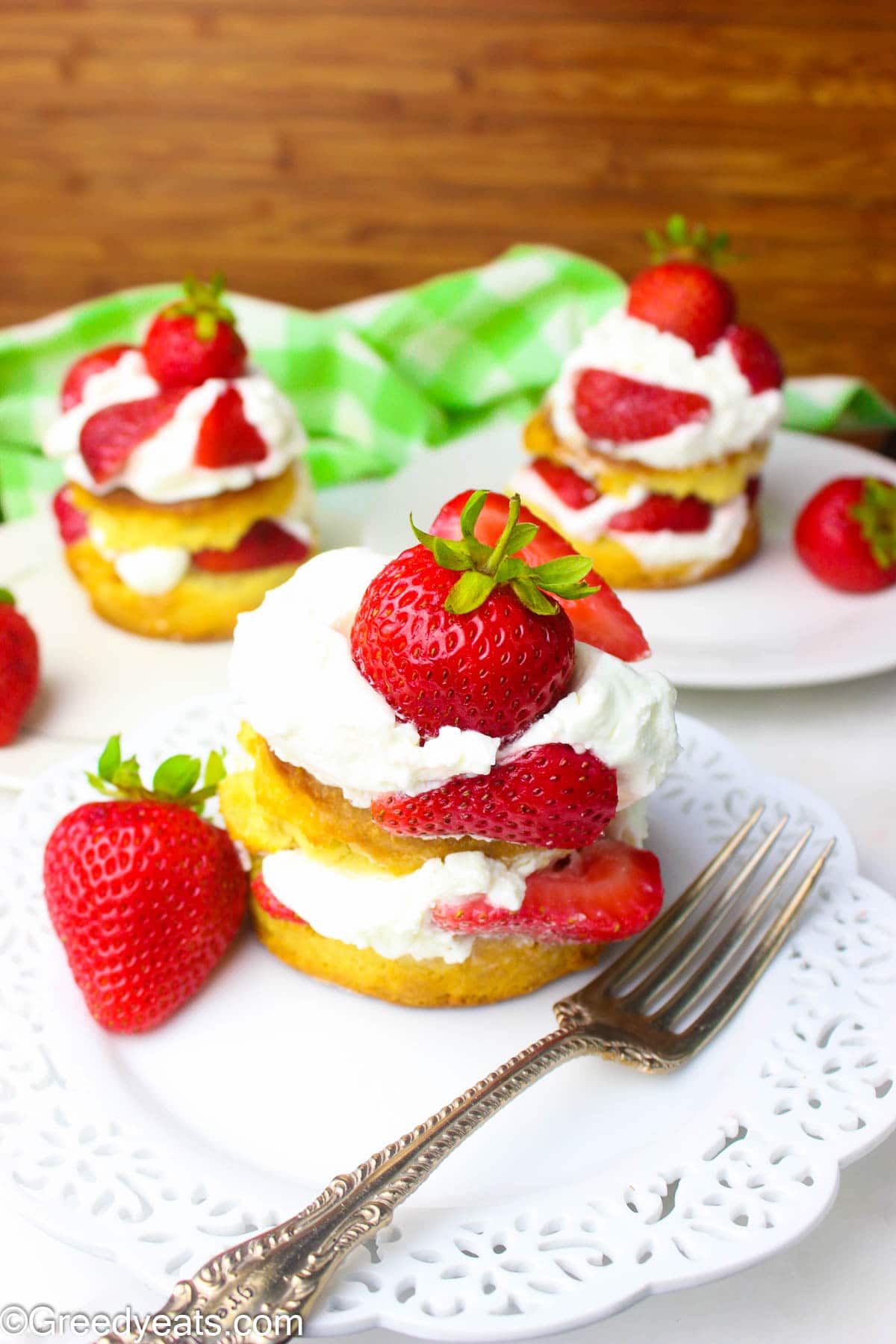 Stacks of layers strawberry shortcake biscuits with whipped cream and straberries.