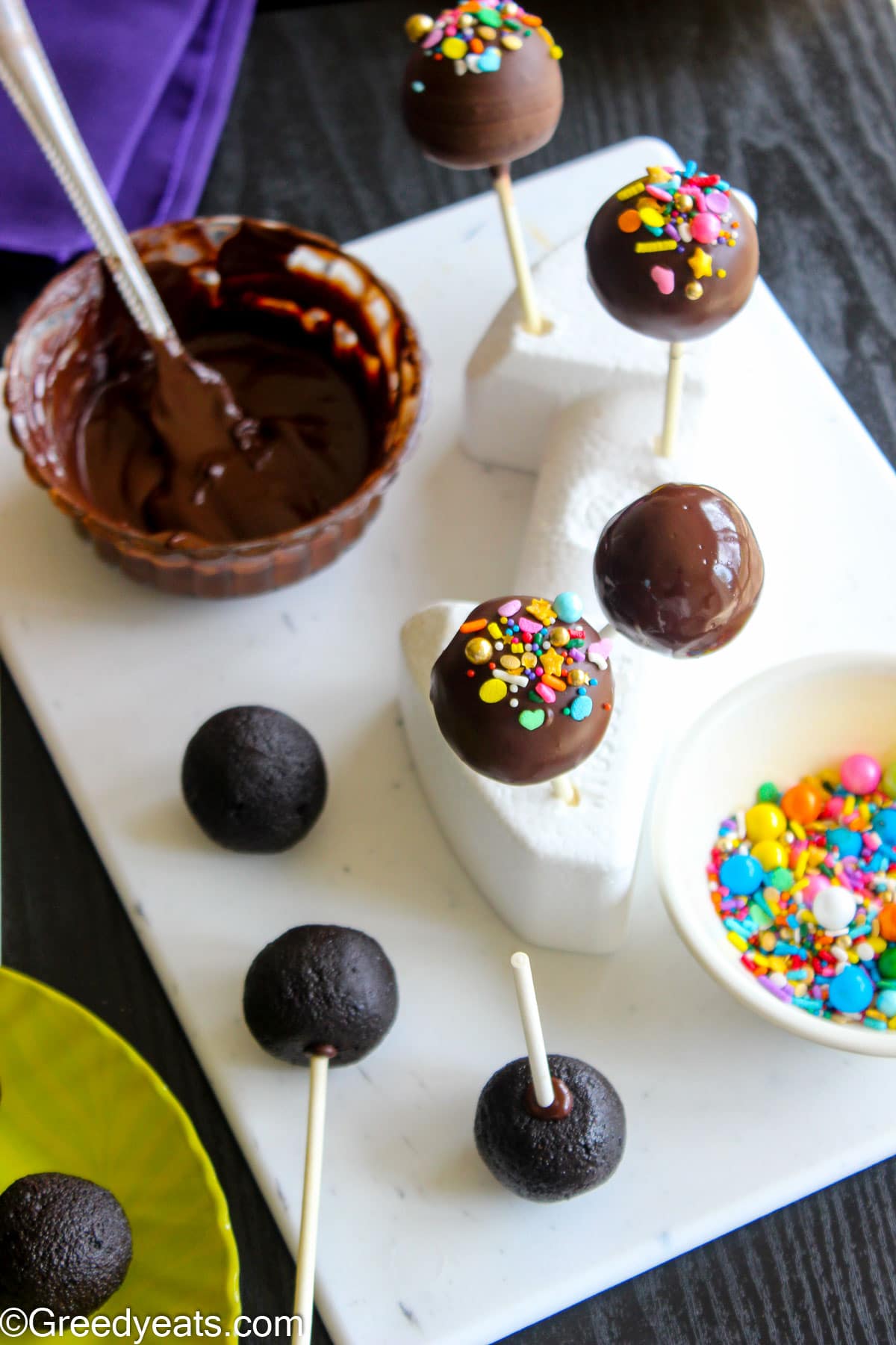 Chocolate Cake Pops getting coated in melted chocolate and setting on styrofoam.