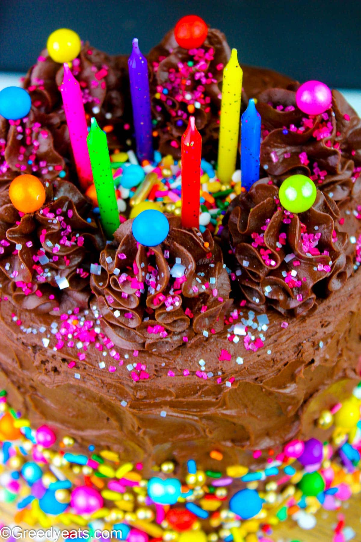 Three layered Chocolate Birthday Cake topped with birthday sprinkles and candles.