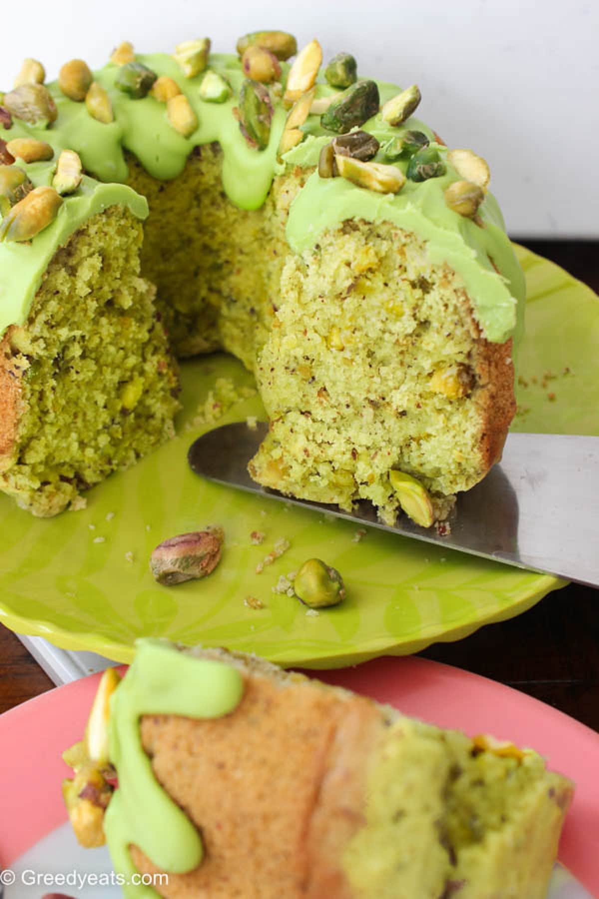 Buttery Pistachio Cake topped with melted chocolate topping and pistachio chunks.