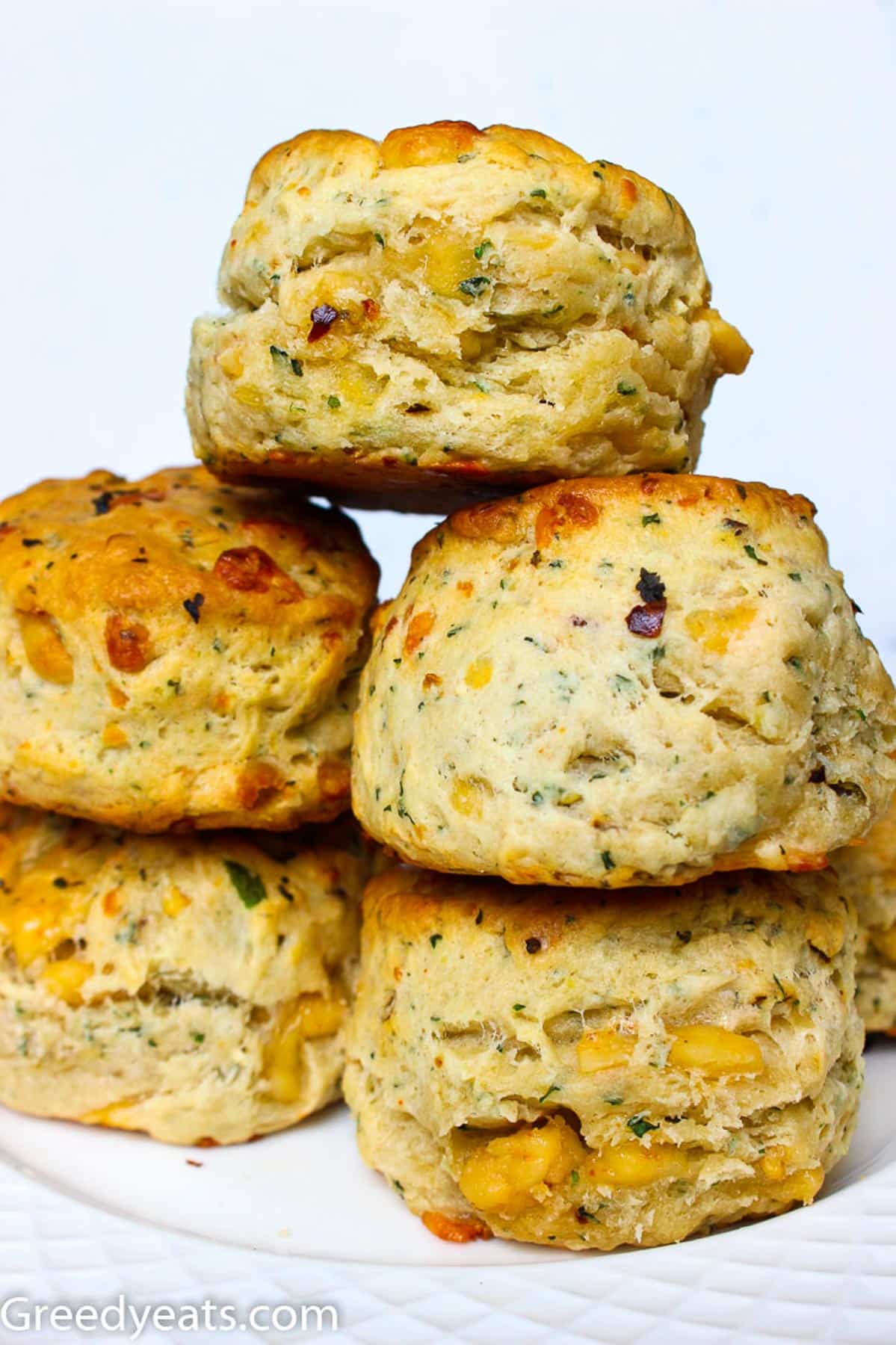 A tall Stack of warm buttery Cheddar Biscuits served on a white plate.. 