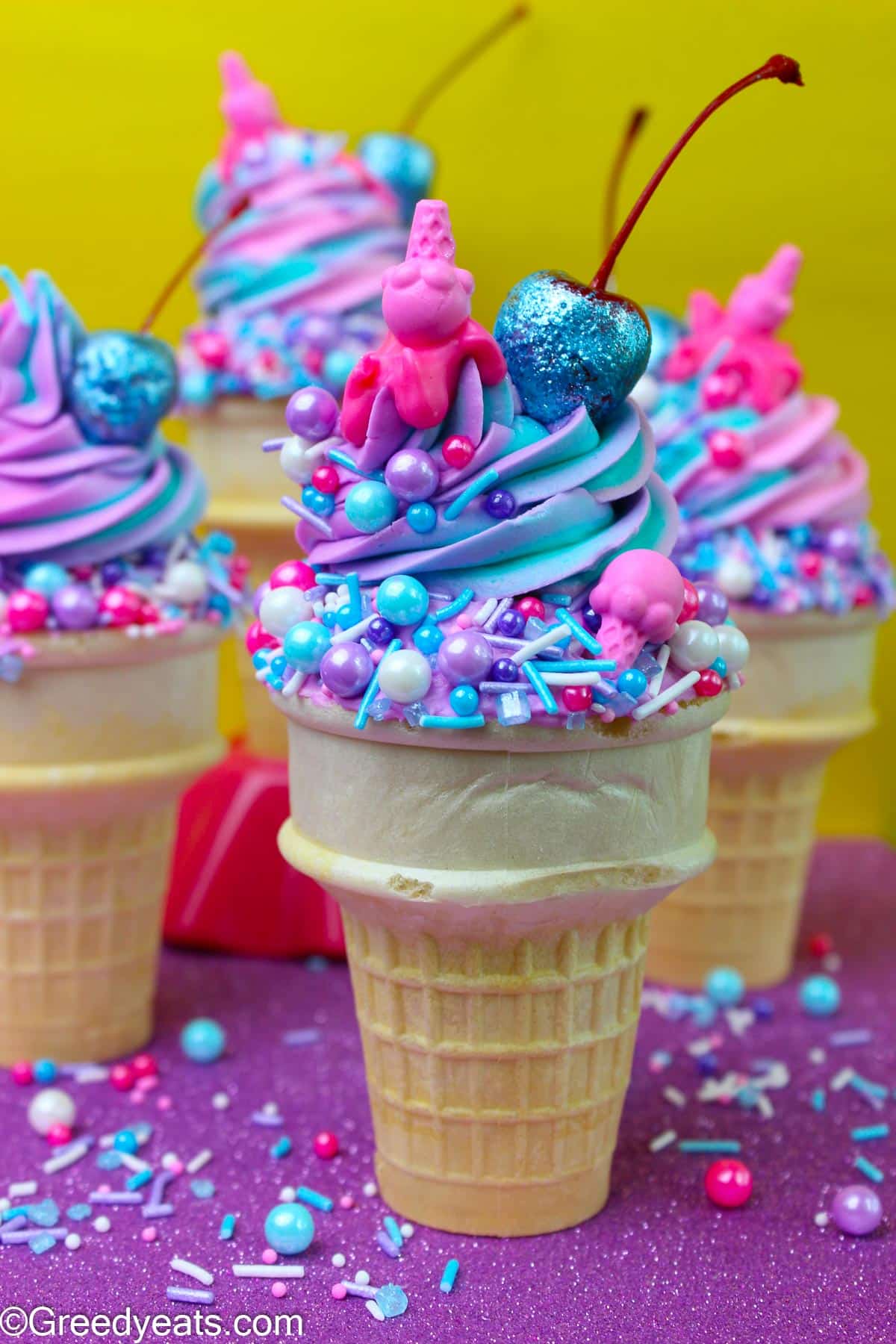 Easy Ice cream cone cupcakes made in cones and topped with swirled frosting, ice cream sprinkles and cherries.