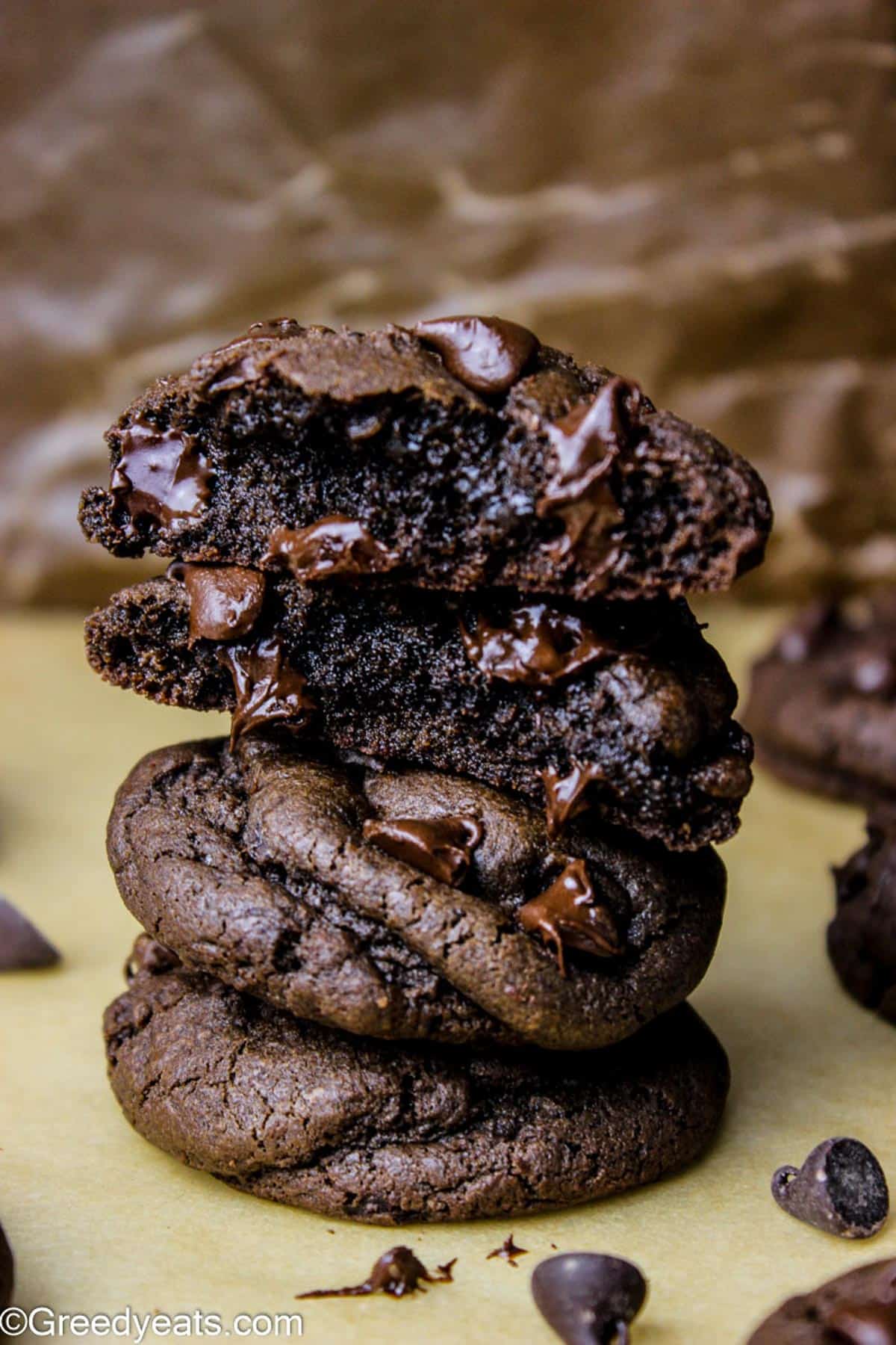 Double Chocolate Chip Cookies stacked on a parchment paper with thick and moist interiors.