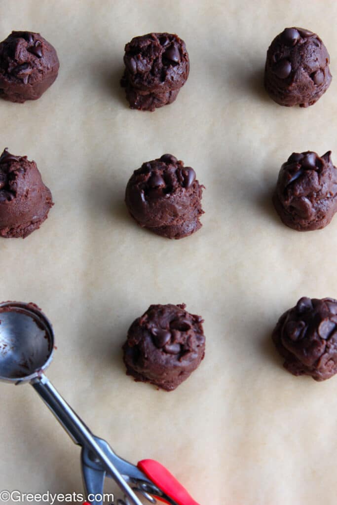 Chocolate cookie dough balls ready to be baked on baking sheet.