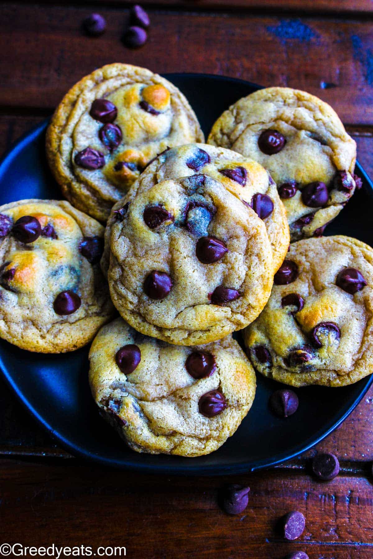 Soft yet chewy cookies with cream cheese and melty chocolate chips all around on a black plate.