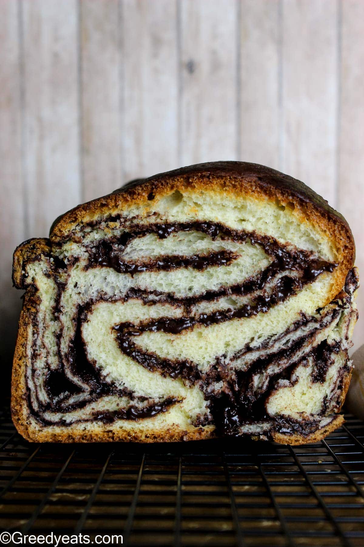 Babka bread made with brioche dough, swirled with easy chocolate filling on a wire stand.