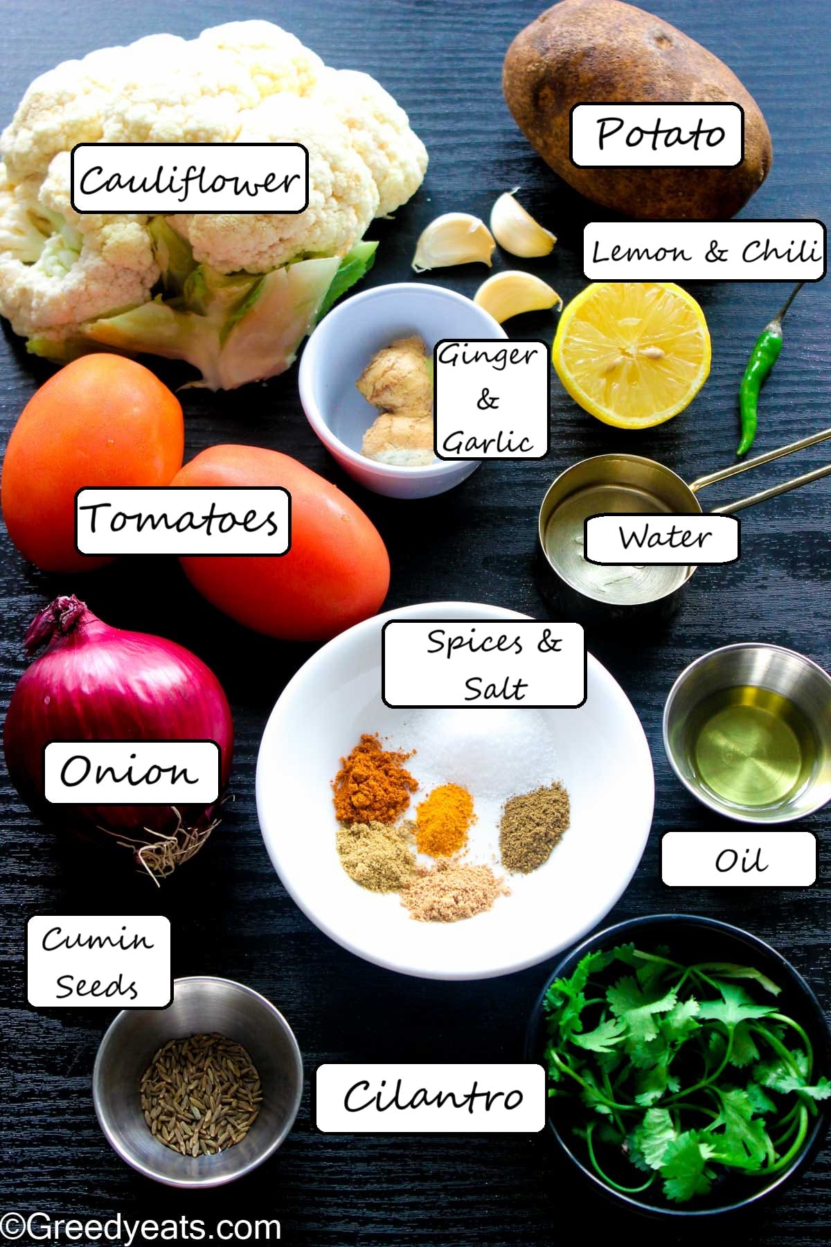 Ingredients like onion, tomatoes, ginger, garlic, potato, cauliflower and spices to make gobi sabji.