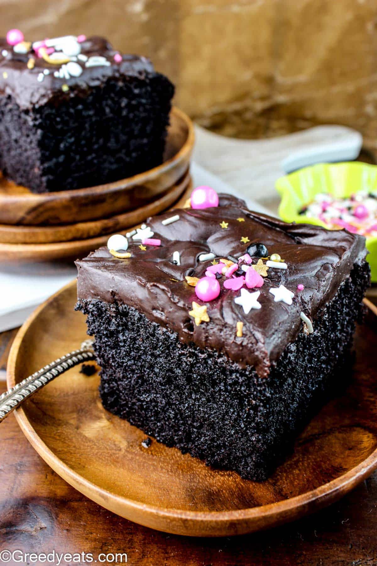 Easy Chocolate Cake with 2 ingredient chocolate ganache, topped with sprinkles on a wooden plate.