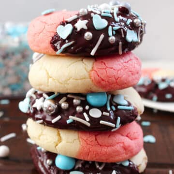 A stack of thick and puffy Neapolitan Cookies dunked in chocolate and topped with sprinkles.