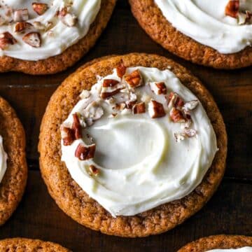 Easy and chewy on the edges Carrot Cake Cookies topped with cream cheese frosting and chopped nuts.