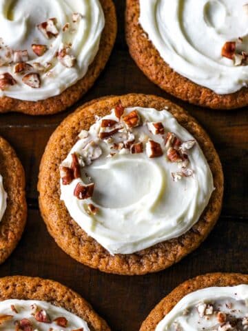 Easy and chewy on the edges Carrot Cake Cookies topped with cream cheese frosting and chopped nuts.