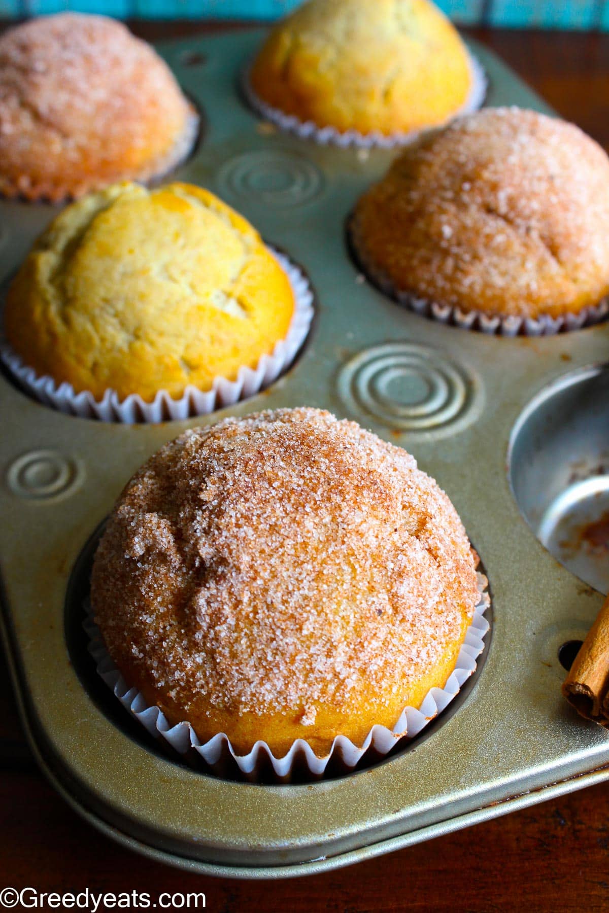 Tall, domed and freshly baked banana muffins in a muffin pan.