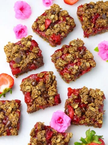 Wholesome breakfast bars squares on a parchment paper with fresh strawberries.