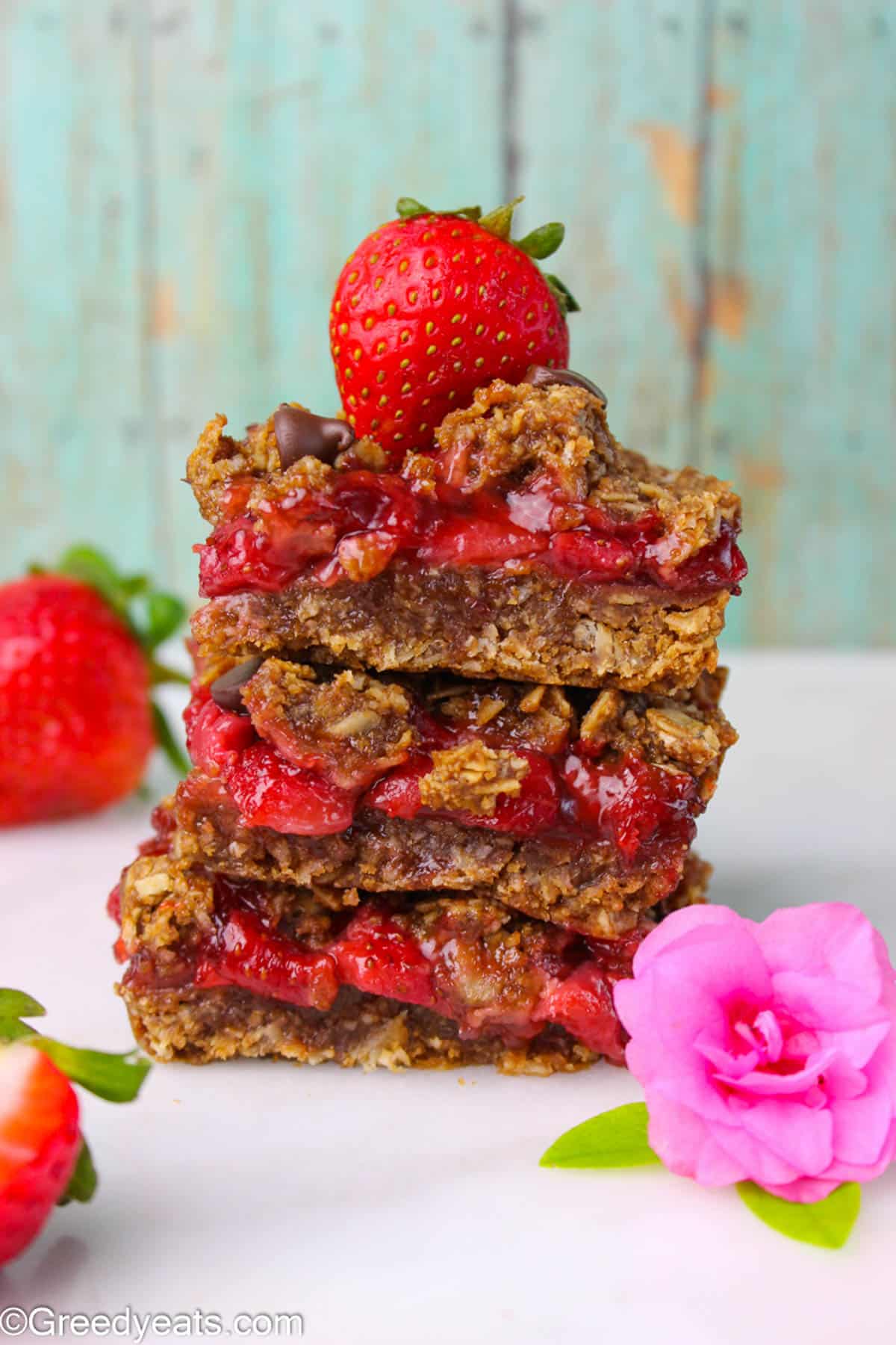 A stack of chewy Strawberry Oatmeal Bars layered with fresh strawberry filling.